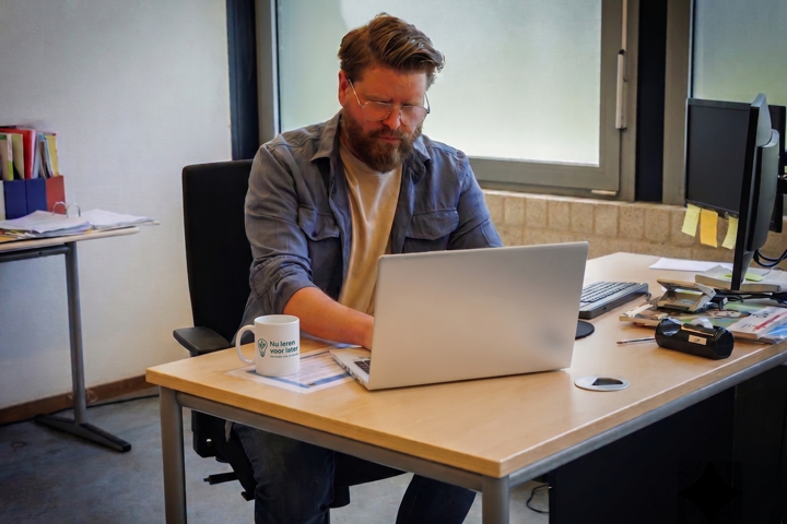 Ramon Visscher werkt aan zijn bureau met laptop en koffie