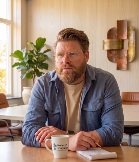 Ramon Visscher aan tafel met een Nu leren voor later koffiemok